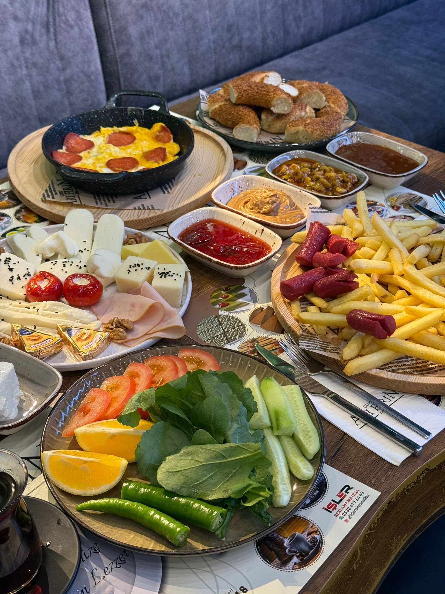 Çorlu Arı Fırın'da sucuklu yumurta, peynir tabağı, sıcak patates kızartması ve taze simit ile dolu zengin serpme kahvaltı sofrası. – Arı Fırın Çorlu